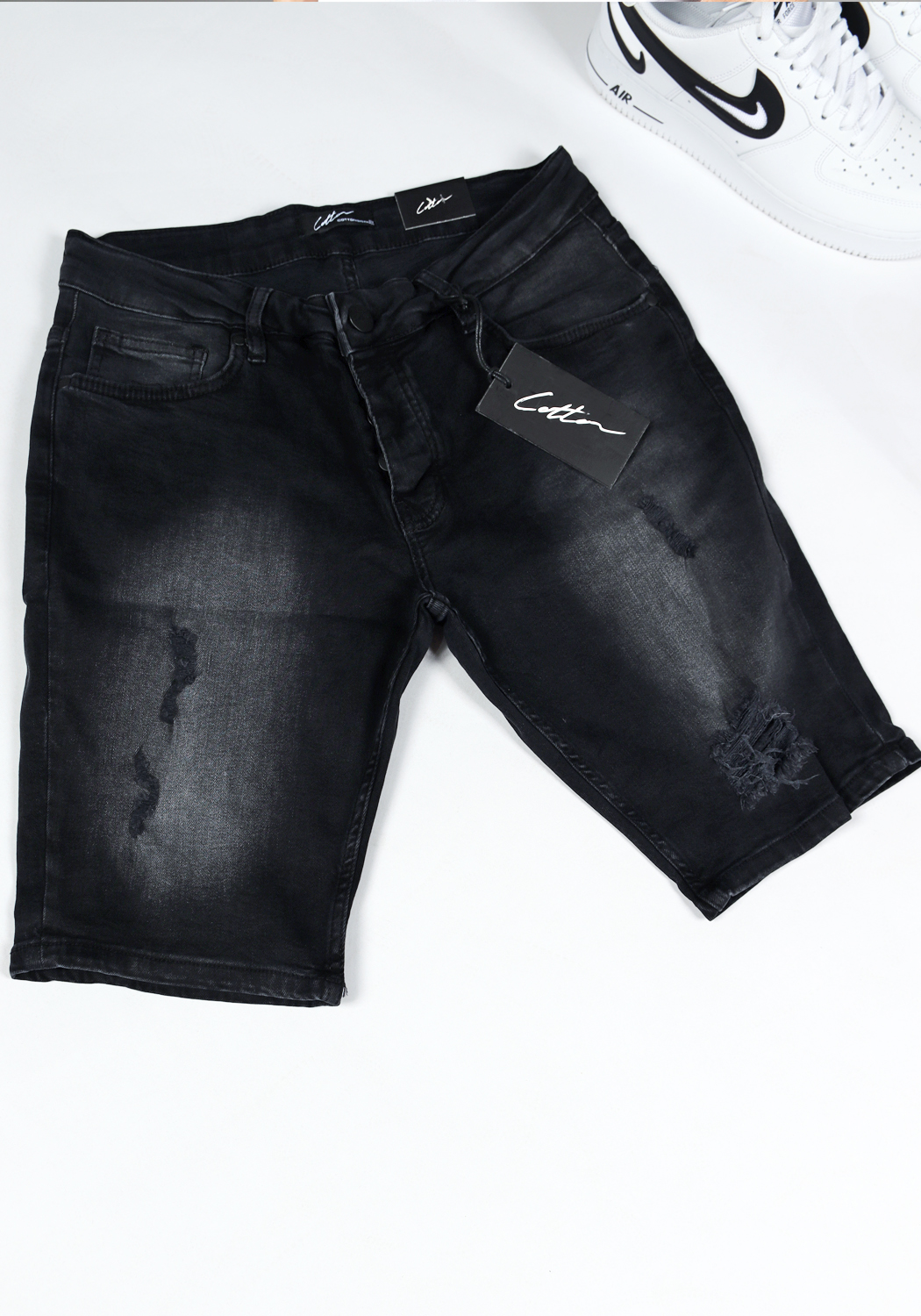 chark shorts 2022 1 Shot bovenaanzicht van zwarte jean shorts met damaged details en een zwart label met het witte signature cotton logo.