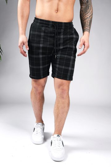 Zwart heren short met ruitjespatroon en slim fit pasvorm. Afgewerkt met twee zakken aan de voorzijde, elastische taille en zwart trekkoord. Gecombineerd met witte sneakers.